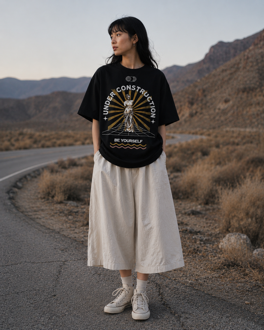 Person wearing a black t-shirt with graphic design in a desert setting. Stylist streetwear tee, comfy formal tee, fashion tee, graphic tee