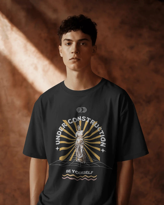 Person wearing a black t-shirt with a graphic design on a brown background