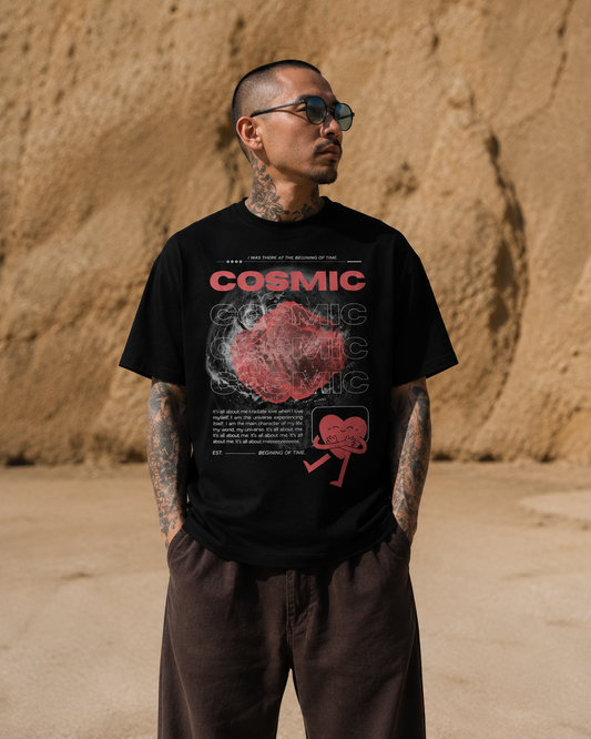 Man wearing a black t-shirt with 'Cosmic' graphic design in a desert setting. Stylist streetwear tee, comfy formal tee, fashion tee, graphic tee