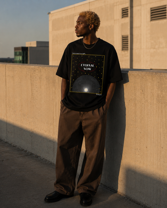 Person wearing a black t-shirt with 'Eternal Now' design on a rooftop. Stylist streetwear tee, comfy formal tee, fashion tee, graphic tee