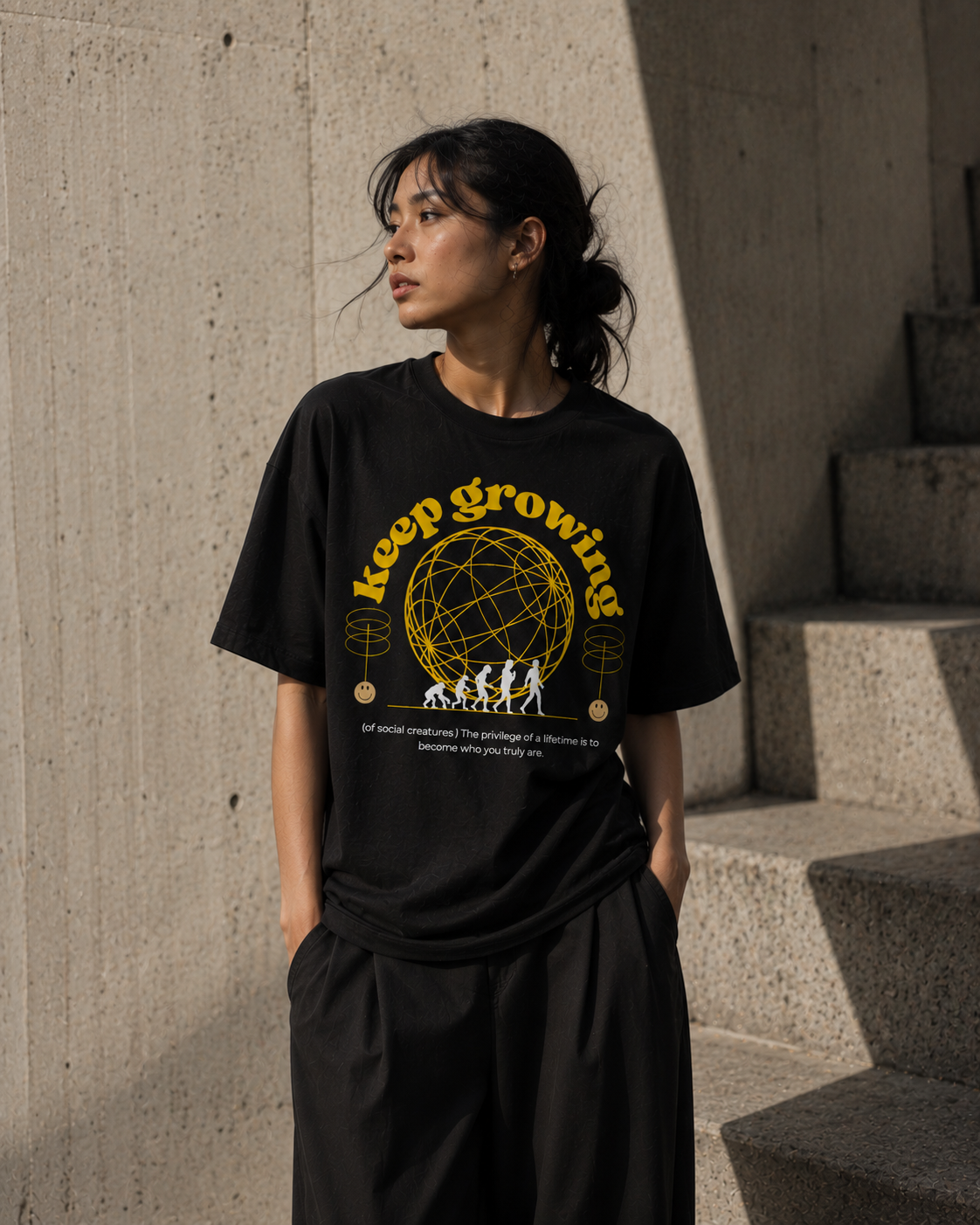 Person wearing a black t-shirt with 'Keep Growing' graphic design outdoors. Stylist streetwear tee, comfy formal tee, fashion tee, graphic tee
