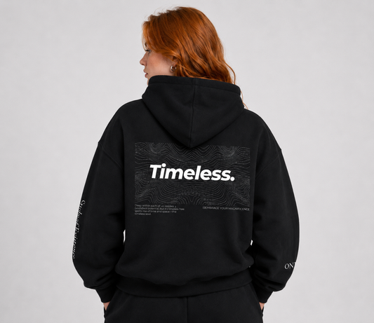 Person wearing a black hoodie with 'Timeless.' text on the back against a gray background. Stylist streetwear hoodie, comfy formal hoodie, fashion hoodie, graphic hoodie, no front pocket hoodie, large hooded hoodie, large hood hoodie, oversized hoodie