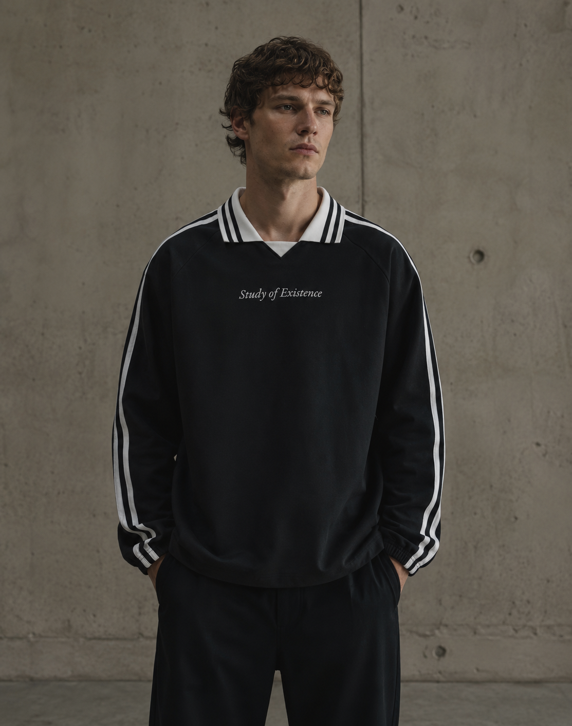 Man wearing a black tracksuit with white stripes and 'Study of Existence' text against a concrete wall. Stylist streetwear collar Sweatshirt, comfy formal collar Sweatshirt, fashion collar Sweatshirt, graphic collar Sweatshirt