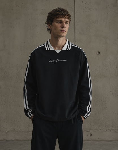 Man wearing a black tracksuit with white stripes and 'Study of Existence' text against a concrete wall. Stylist streetwear collar Sweatshirt, comfy formal collar Sweatshirt, fashion collar Sweatshirt, graphic collar Sweatshirt
