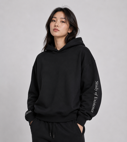 Person wearing a black hoodie with text on sleeves against a gray background.Stylist streetwear hoodie, comfy formal hoodie, fashion hoodie, graphic hoodie, no front pocket hoodie, large hooded hoodie, large hood hoodie, oversized hoodie
