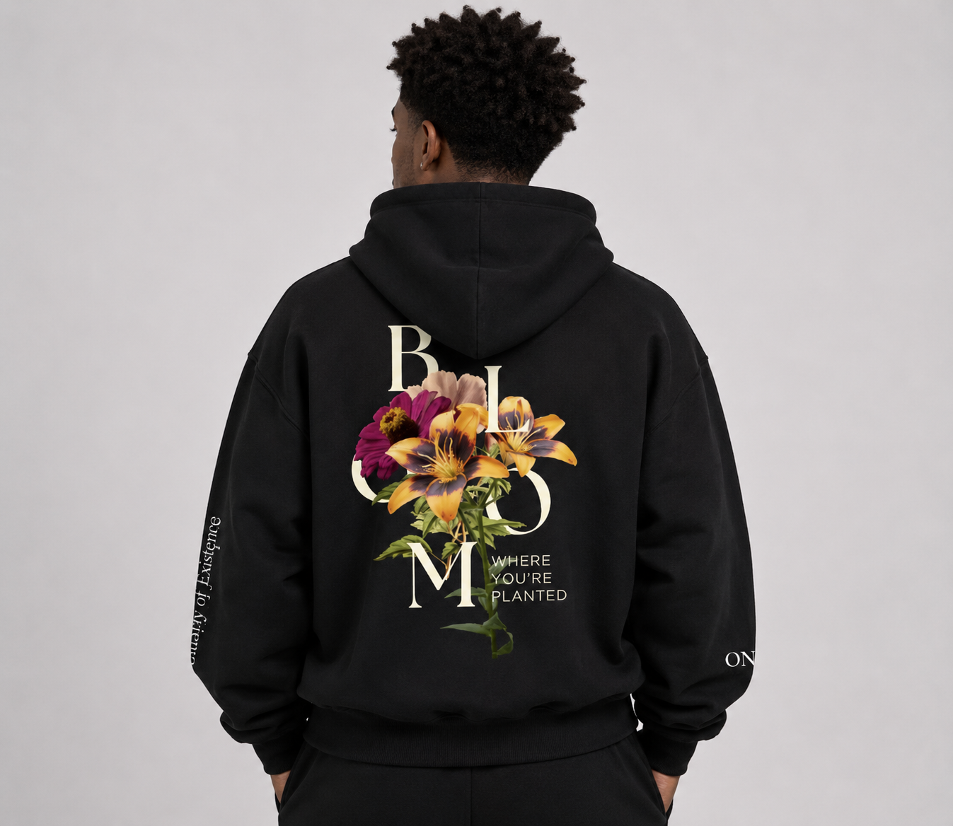 Person wearing a black hoodie with floral design and text on the back against a gray background. Stylist streetwear hoodie, comfy formal hoodie, fashion hoodie, graphic hoodie, no front pocket hoodie, large hooded hoodie, large hood hoodie, oversized hoodie