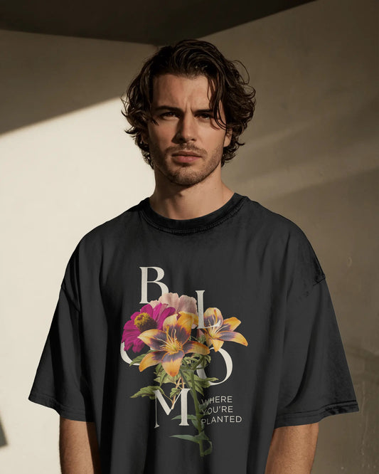 Man wearing a black t-shirt with floral design and text against a neutral background