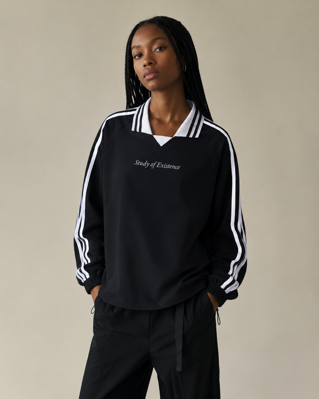 Person wearing a black tracksuit with white stripes on a beige background. Stylist streetwear collar Sweatshirt, comfy formal collar Sweatshirt, fashion collar Sweatshirt, graphic collar Sweatshirt