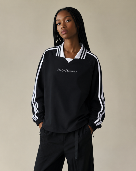 Person wearing a black tracksuit with white stripes on a beige background. Stylist streetwear collar Sweatshirt, comfy formal collar Sweatshirt, fashion collar Sweatshirt, graphic collar Sweatshirt