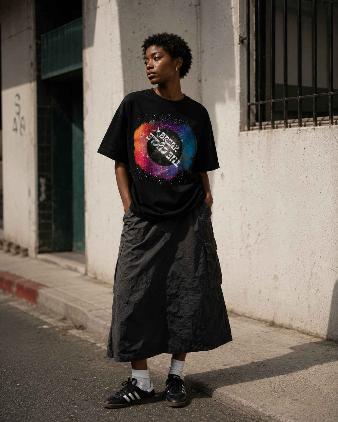 Person wearing a black t-shirt with a colorful graphic design, standing on a street. Stylist streetwear tee, comfy formal tee, fashion tee, graphic tee