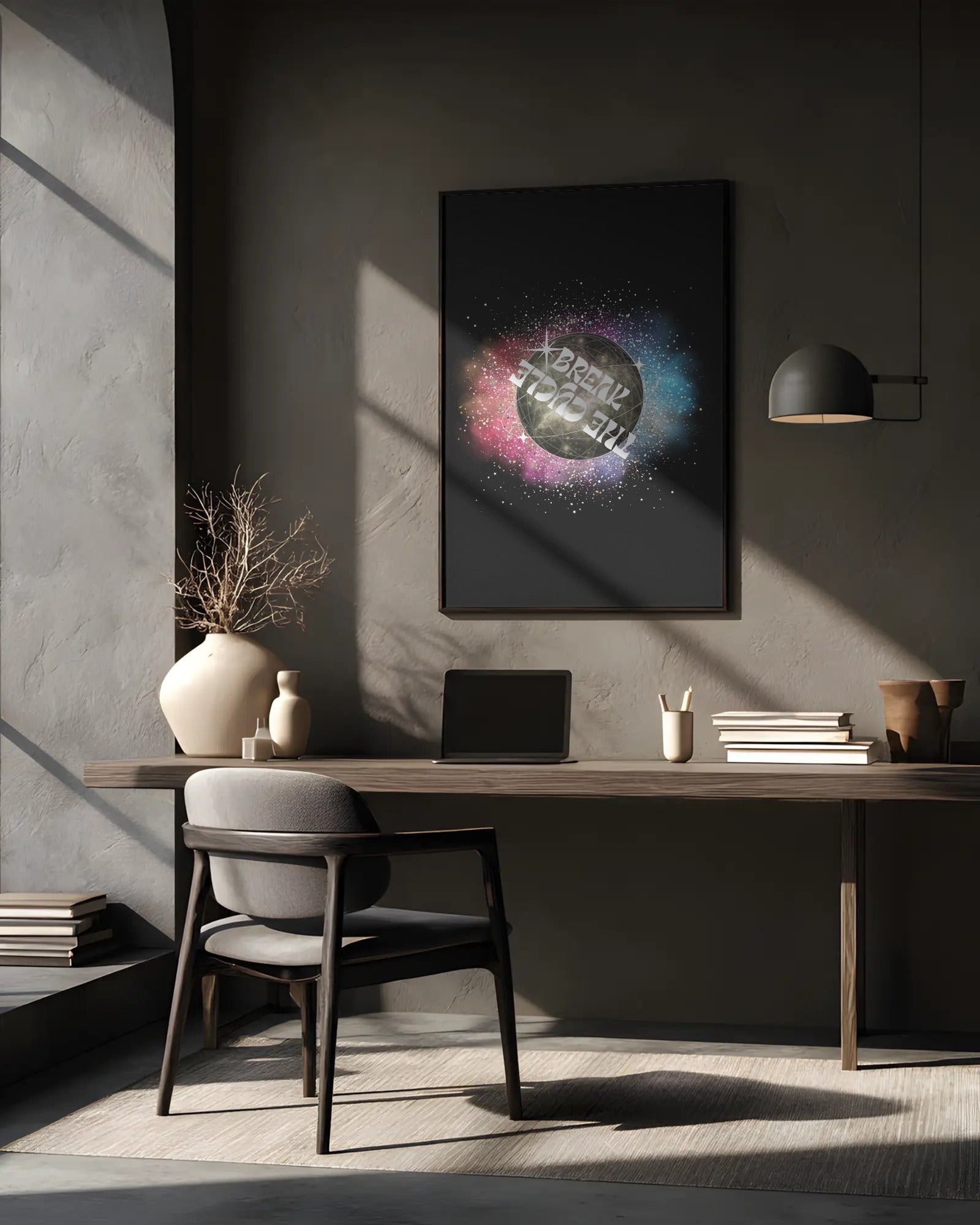 Modern office desk with a laptop, books, and decorative items against a gray wall with a framed abstract art piece.
