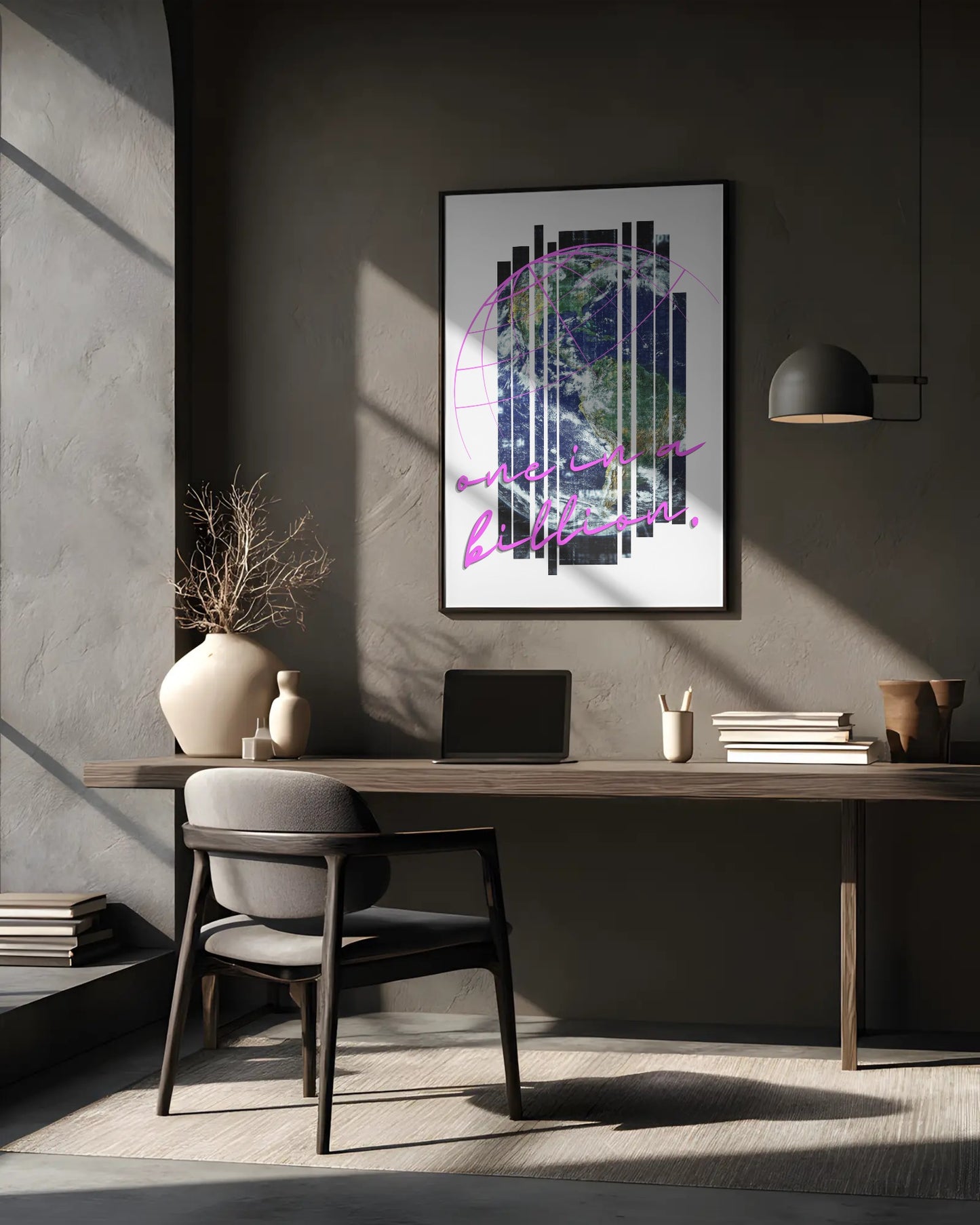 Modern office desk with a laptop, books, and decorative items against a gray wall with a framed abstract art piece.