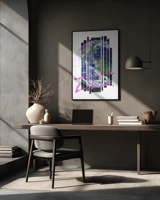 Modern office desk with a laptop, books, and decorative items against a gray wall with a framed abstract art piece.