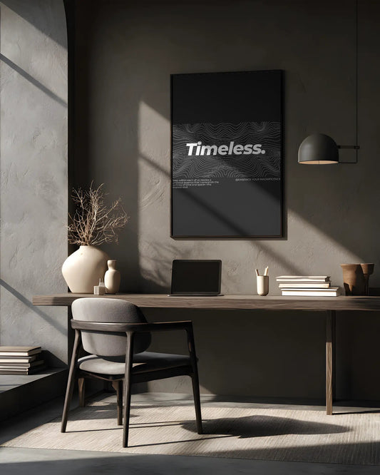Modern office desk with a laptop, books, and a vase in a room with a 'Timeless' poster on the wall.
