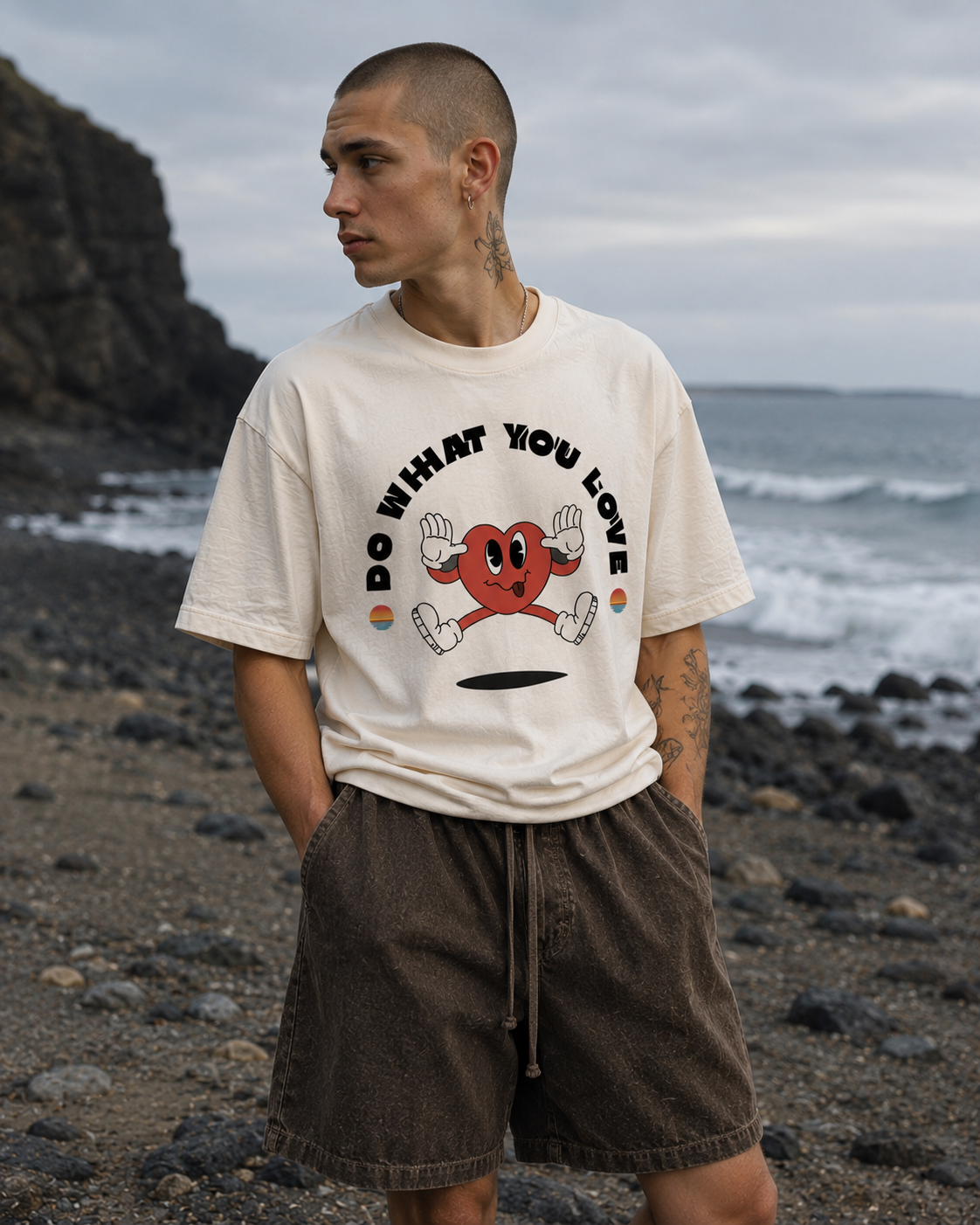 Man wearing a t-shirt with a graphic design on a rocky beach. Stylist streetwear tee, comfy formal tee, fashion tee, graphic tee