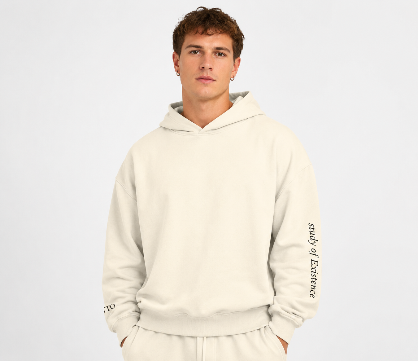 Man wearing a beige hoodie with text on sleeves against a white background. Stylist streetwear hoodie, comfy formal hoodie, fashion hoodie, graphic hoodie, no front pocket hoodie, large hooded hoodie, large hood hoodie, oversized hoodie