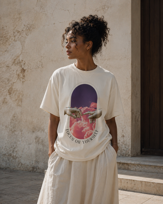 Person wearing a white t-shirt with a graphic design and text, standing against a textured wall. Stylist streetwear tee, comfy formal tee, fashion tee, graphic tee