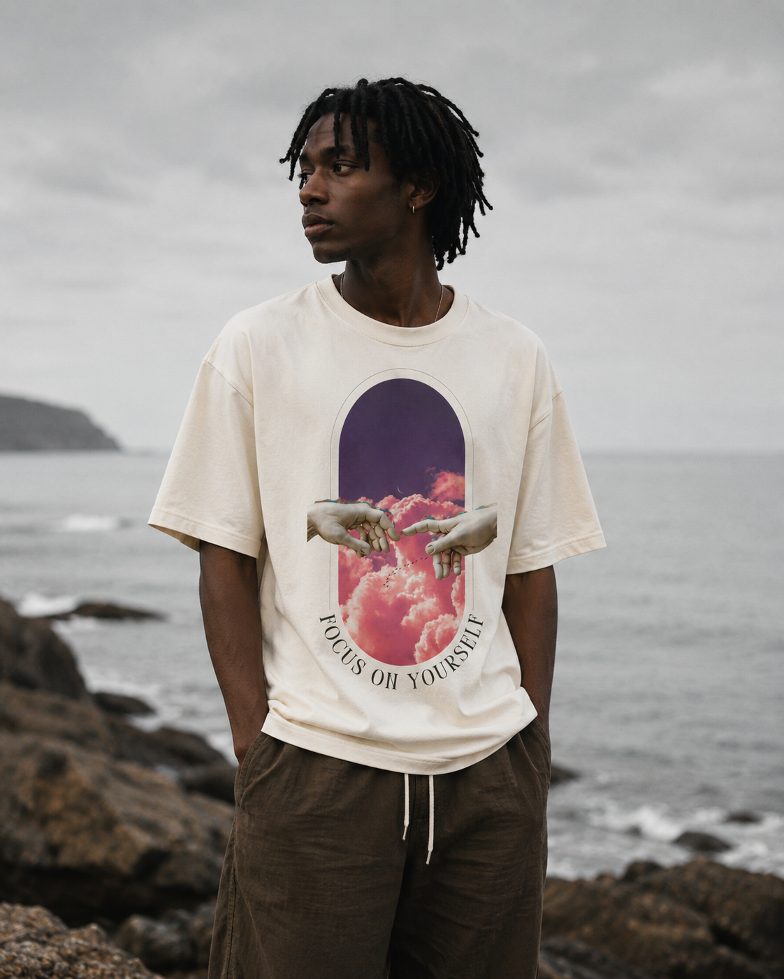 Person wearing a t-shirt with a graphic design by the sea. Stylist streetwear tee, comfy formal tee, fashion tee, graphic tee