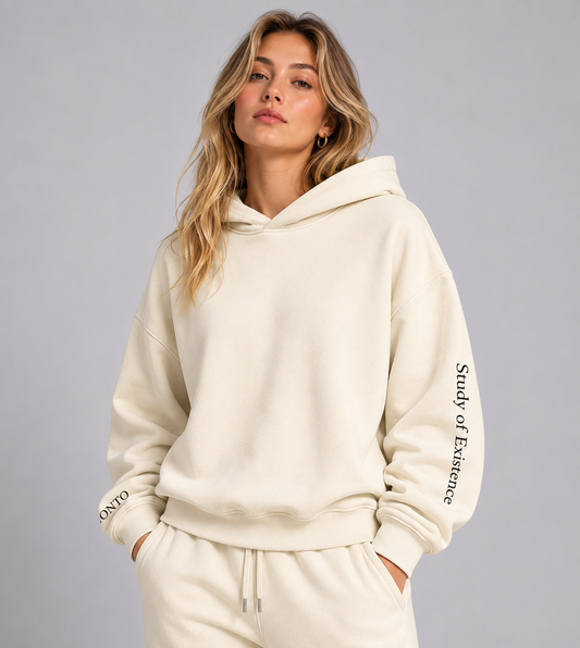 Person wearing a cream-colored hoodie with 'Study of Existence' branding on a gray background. Stylist streetwear hoodie, comfy formal hoodie, fashion hoodie, graphic hoodie, no front pocket hoodie, large hooded hoodie, large hood hoodie, oversized hoodie