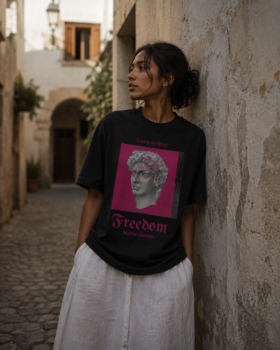 Woman wearing a black t-shirt with a graphic design and text, standing against a textured wall. Stylist streetwear tee, comfy formal tee, fashion tee, graphic tee