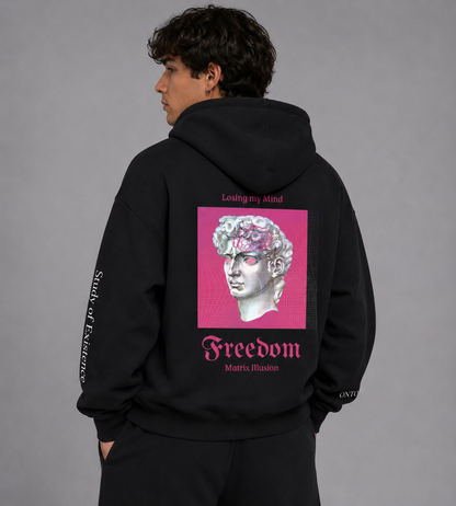Person wearing a Black hoodie with a pink graphic and text on the back against a white background. Stylist streetwear hoodie, comfy formal hoodie, fashion hoodie, graphic hoodie, no front pocket hoodie, large hooded hoodie, large hood hoodie, oversized hoodie