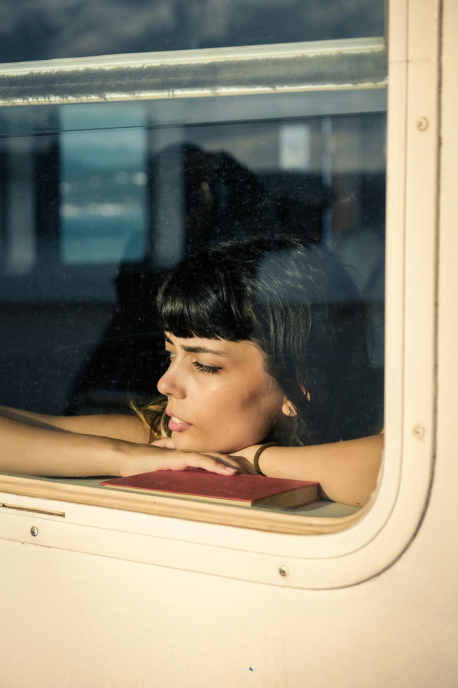 Woman looking out of a window with a blurred cityscape in the background
