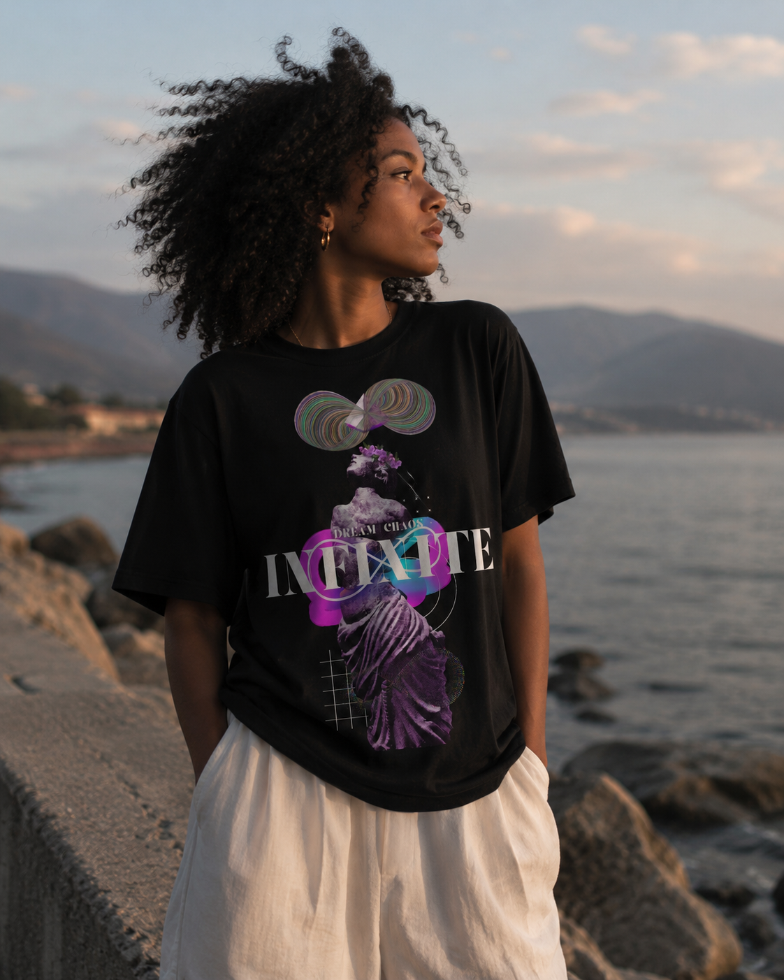 Person wearing a black t-shirt with a colorful graphic design by the sea Stylist streetwear tee, comfy formal tee, fashion tee, graphic tee