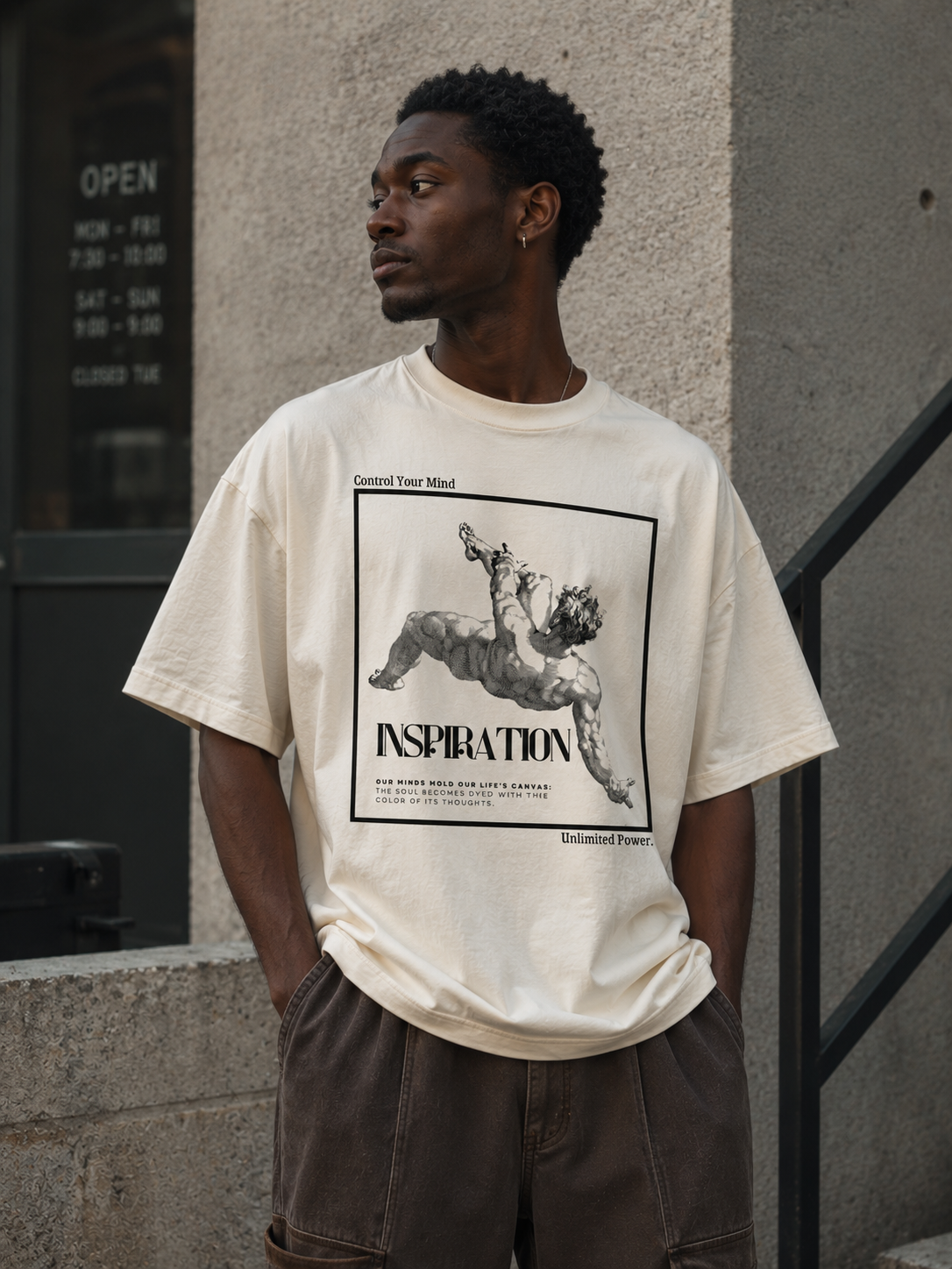 Man wearing a white t-shirt with a graphic design standing against a building.Stylist streetwear tee, comfy formal tee, fashion tee, graphic tee