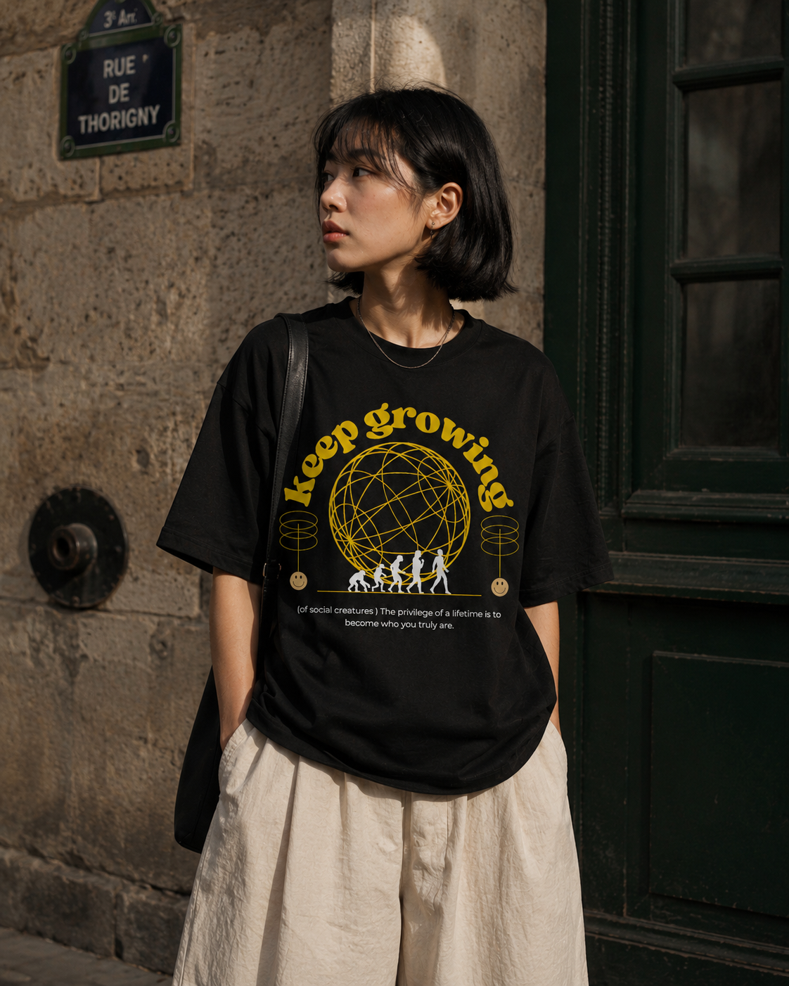 Person wearing a black t-shirt with yellow text and graphics in an urban setting. Stylist streetwear tee, comfy formal tee, fashion tee, graphic tee