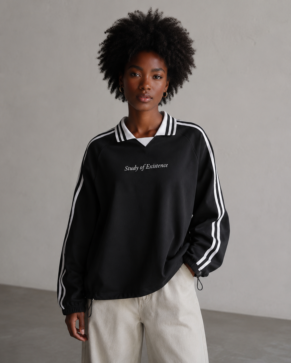 Person wearing a black sweatshirt with white stripes and text, standing against a plain background. Stylist streetwear collar Sweatshirt, comfy formal collar Sweatshirt, fashion collar Sweatshirt, graphic collar Sweatshirt