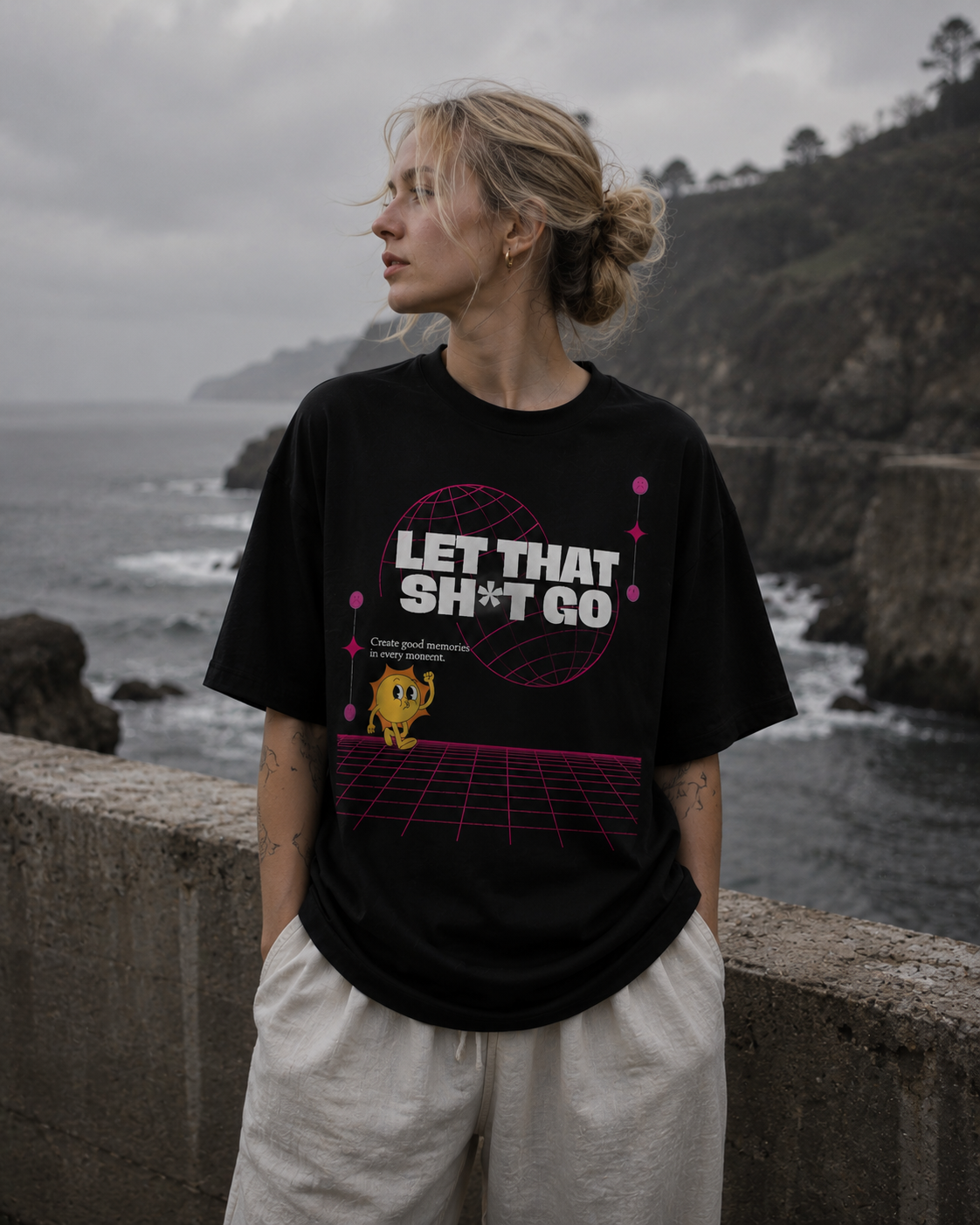 Person wearing a black t-shirt with a graphic design by the ocean. Stylist streetwear tee, comfy formal tee, fashion tee, graphic tee