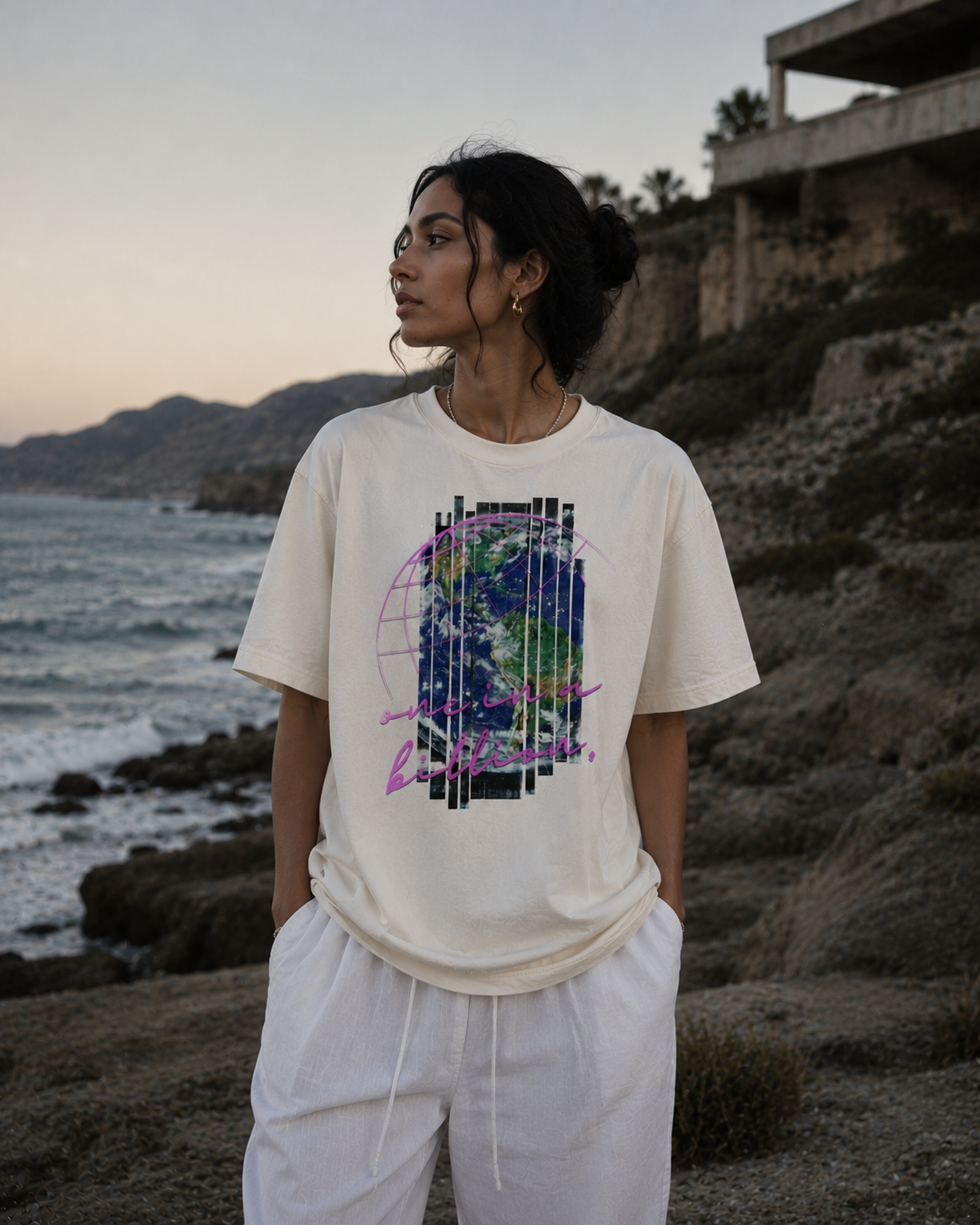 Person wearing a graphic t-shirt by the ocean with mountains in the background.Stylist streetwear tee, comfy formal tee, fashion tee, graphic tee