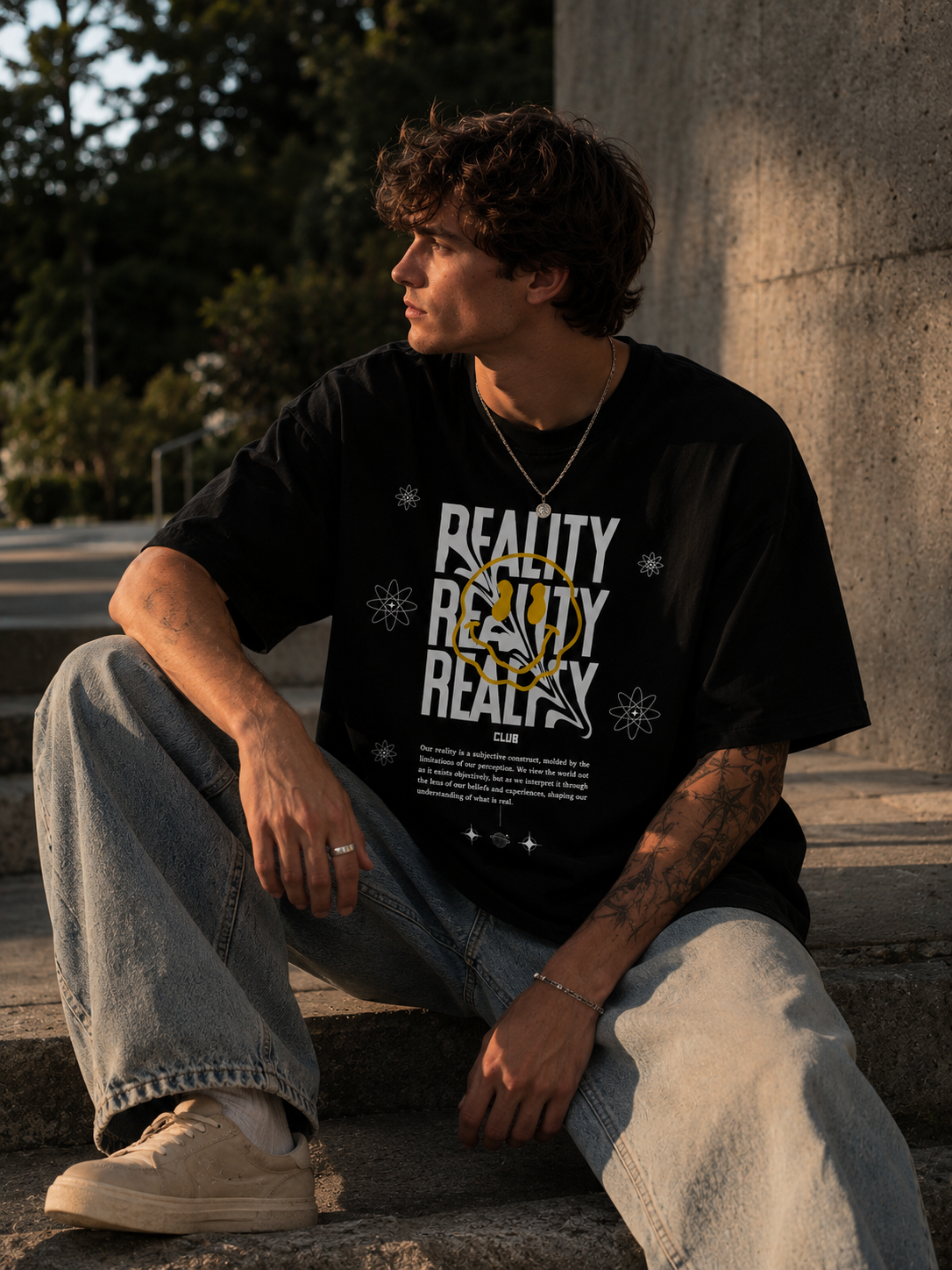 Person wearing a black t-shirt with 'REALITY' text sitting outdoors.Stylist streetwear tee, comfy formal tee, fashion tee, graphic tee