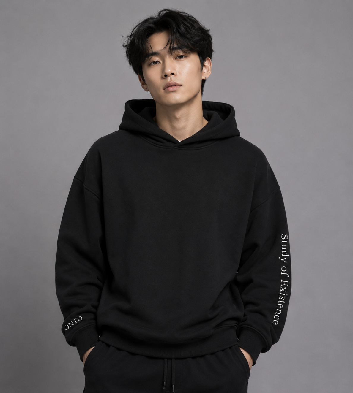 Person wearing a black hoodie with text on a gray background. Black hoodie with text on sleeves against a white background. Stylist streetwear hoodie, comfy formal hoodie, fashion hoodie, graphic hoodie, no front pocket hoodie, large hooded hoodie, large hood hoodie, oversized hoodie