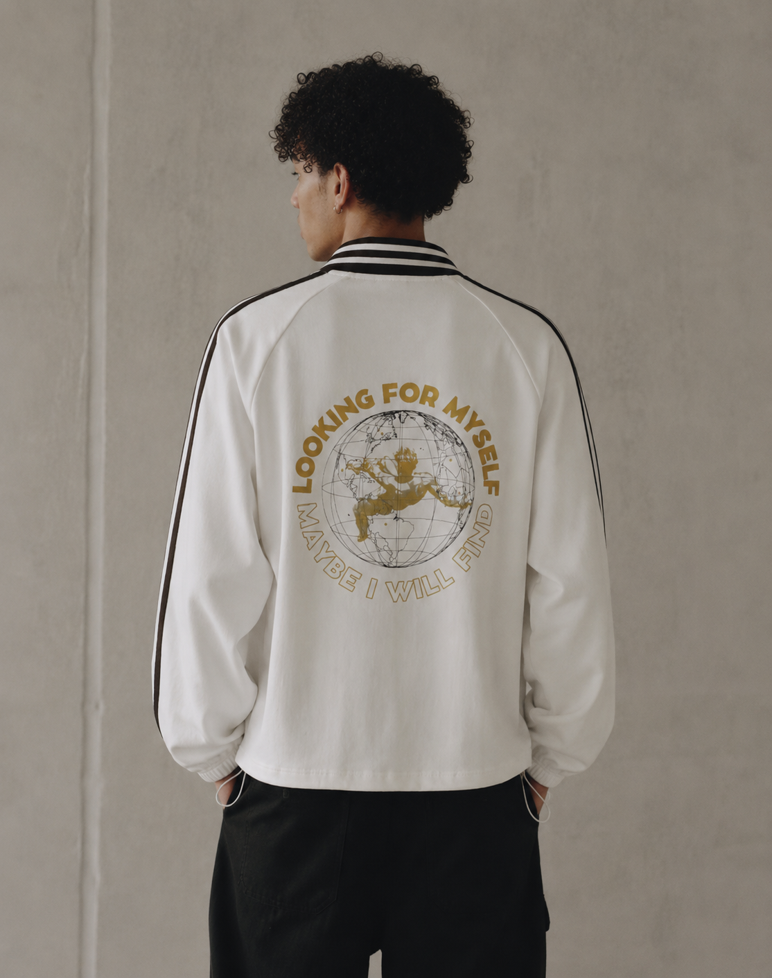 Person wearing a white jacket with text and graphics on the back, standing against a plain wall. Stylist streetwear collar Sweatshirt, comfy formal collar Sweatshirt, fashion collar Sweatshirt, graphic collar Sweatshirt