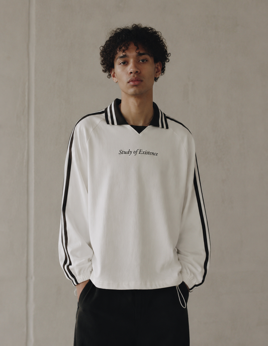 Person wearing a white tracksuit with black stripes and text, standing against a plain background. Stylist streetwear collar Sweatshirt, comfy formal collar Sweatshirt, fashion collar Sweatshirt, graphic collar Sweatshirt