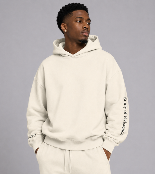 Man wearing a beige hoodie with text on sleeves against a gray background. Stylist streetwear hoodie, comfy formal hoodie, fashion hoodie, graphic hoodie, no front pocket hoodie, large hooded hoodie, large hood hoodie, oversized hoodie