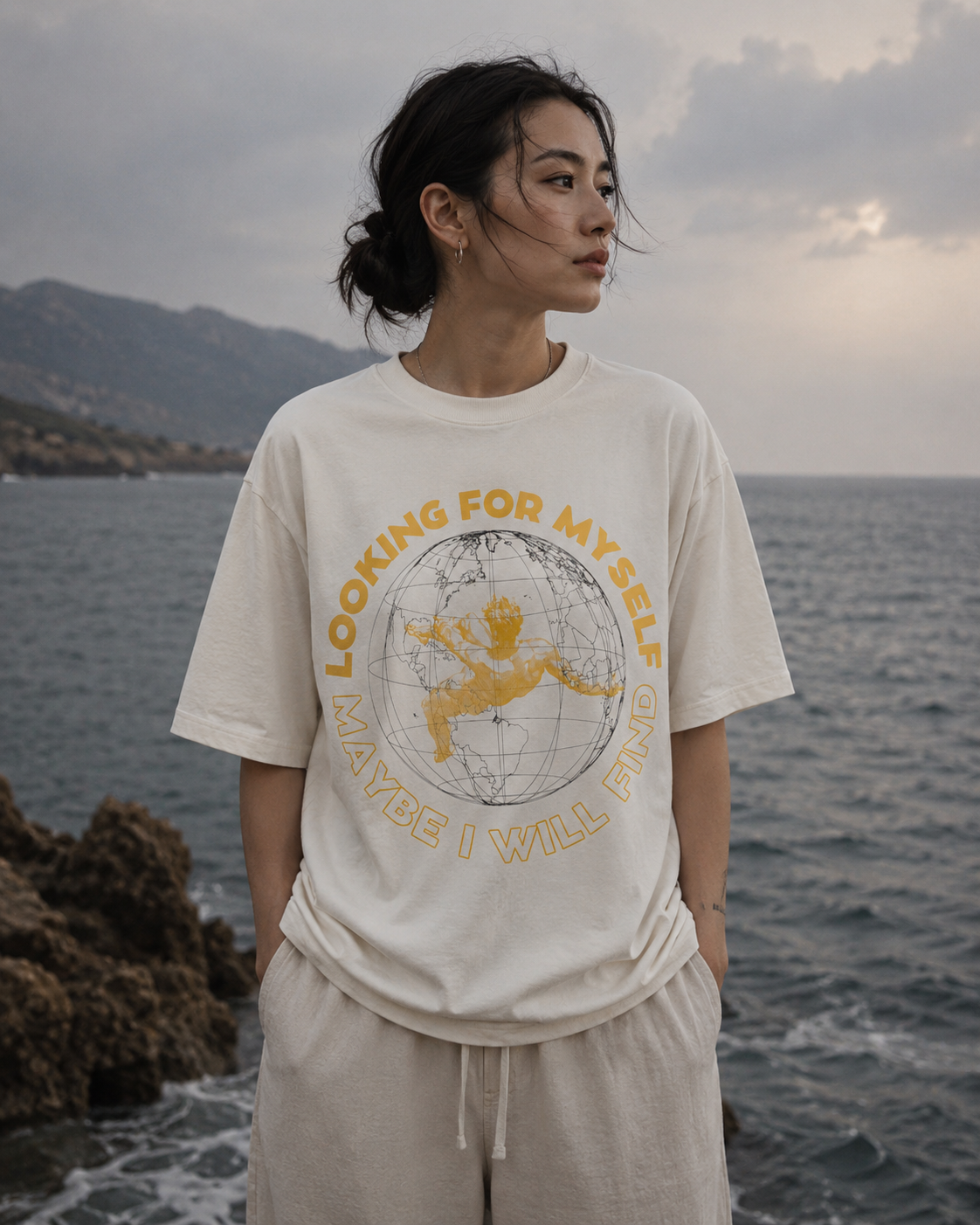 Person wearing a t-shirt with a graphic design and text by the sea Stylist streetwear tee, comfy formal tee, fashion tee, graphic tee