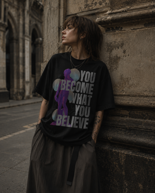 Person wearing a black t-shirt with a motivational quote, leaning against a stone wall. Stylist streetwear tee, comfy formal tee, fashion tee, graphic tee
