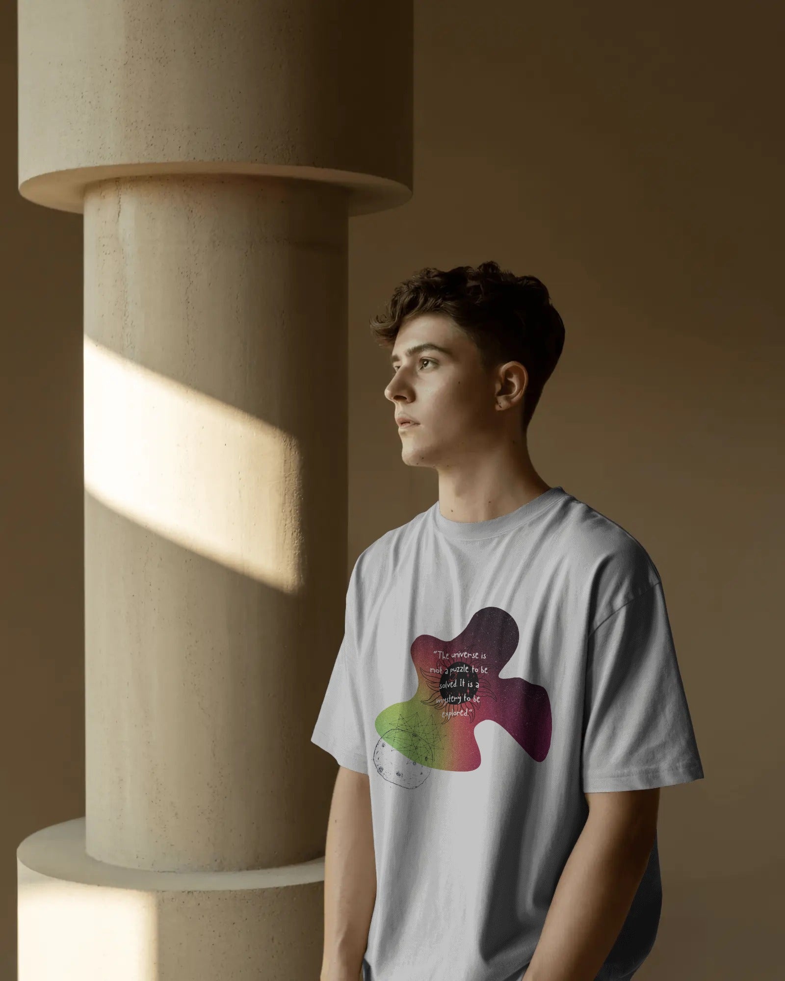 Person wearing a t-shirt with a colorful design in a warm-toned room.