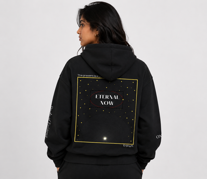 Person wearing a black hoodie with 'Eternal Now' design on the back against a white background. Stylist streetwear hoodie, comfy formal hoodie, fashion hoodie, graphic hoodie, no front pocket hoodie, large hooded hoodie, large hood hoodie, oversized hoodie