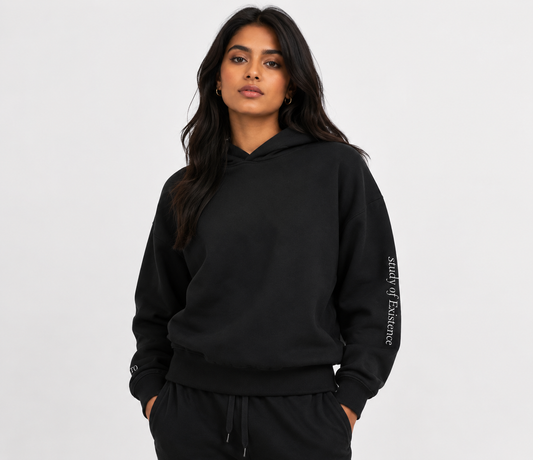 Person wearing a black hoodie with text on sleeve against a white background. Stylist streetwear hoodie, comfy formal hoodie, fashion hoodie, graphic hoodie, no front pocket hoodie, large hooded hoodie, large hood hoodie, oversized hoodie