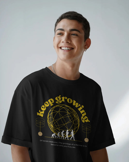 Person wearing a black t-shirt with 'keep growing' graphic design on a plain background