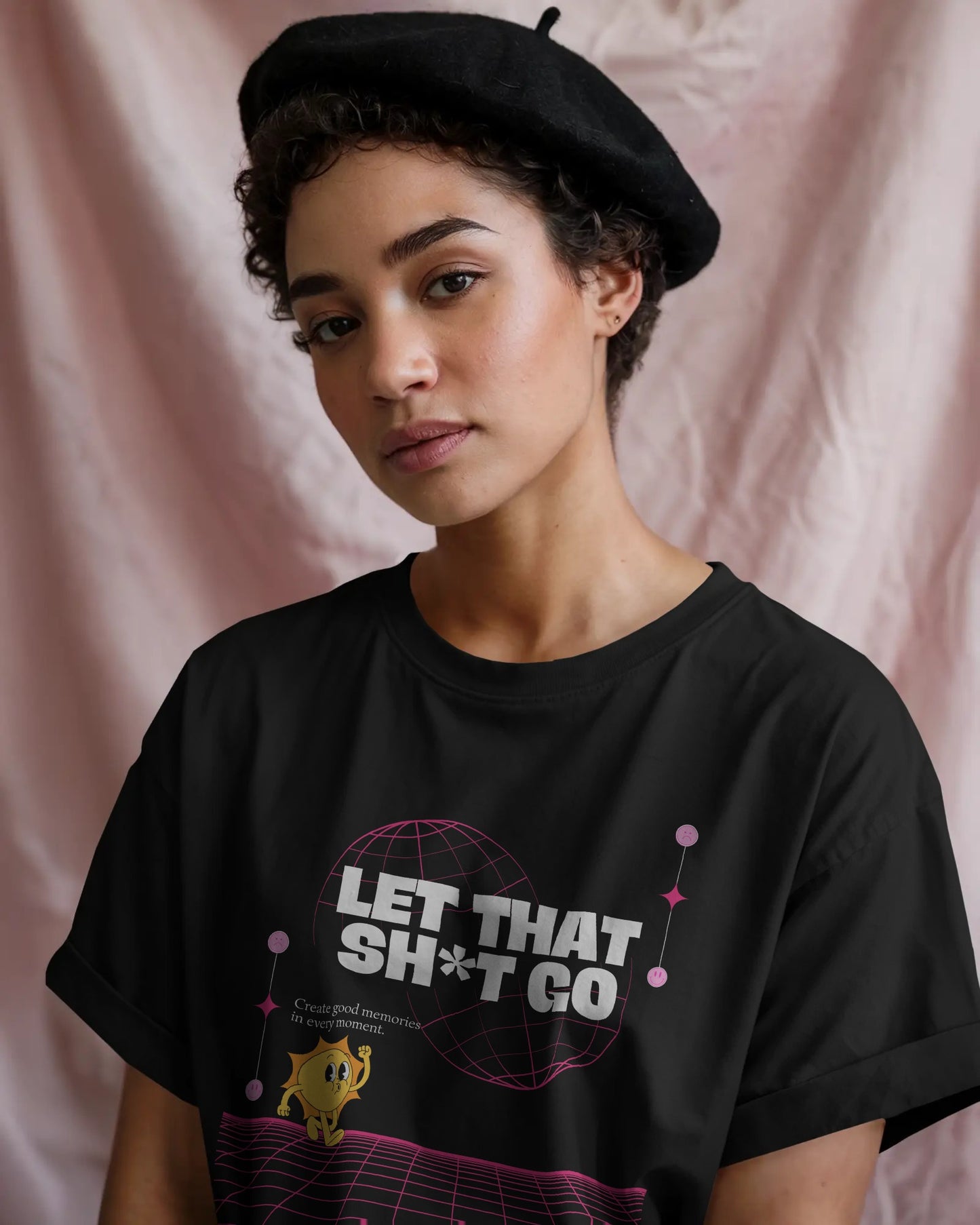 Person wearing a black t-shirt with text and graphic design against a pink background