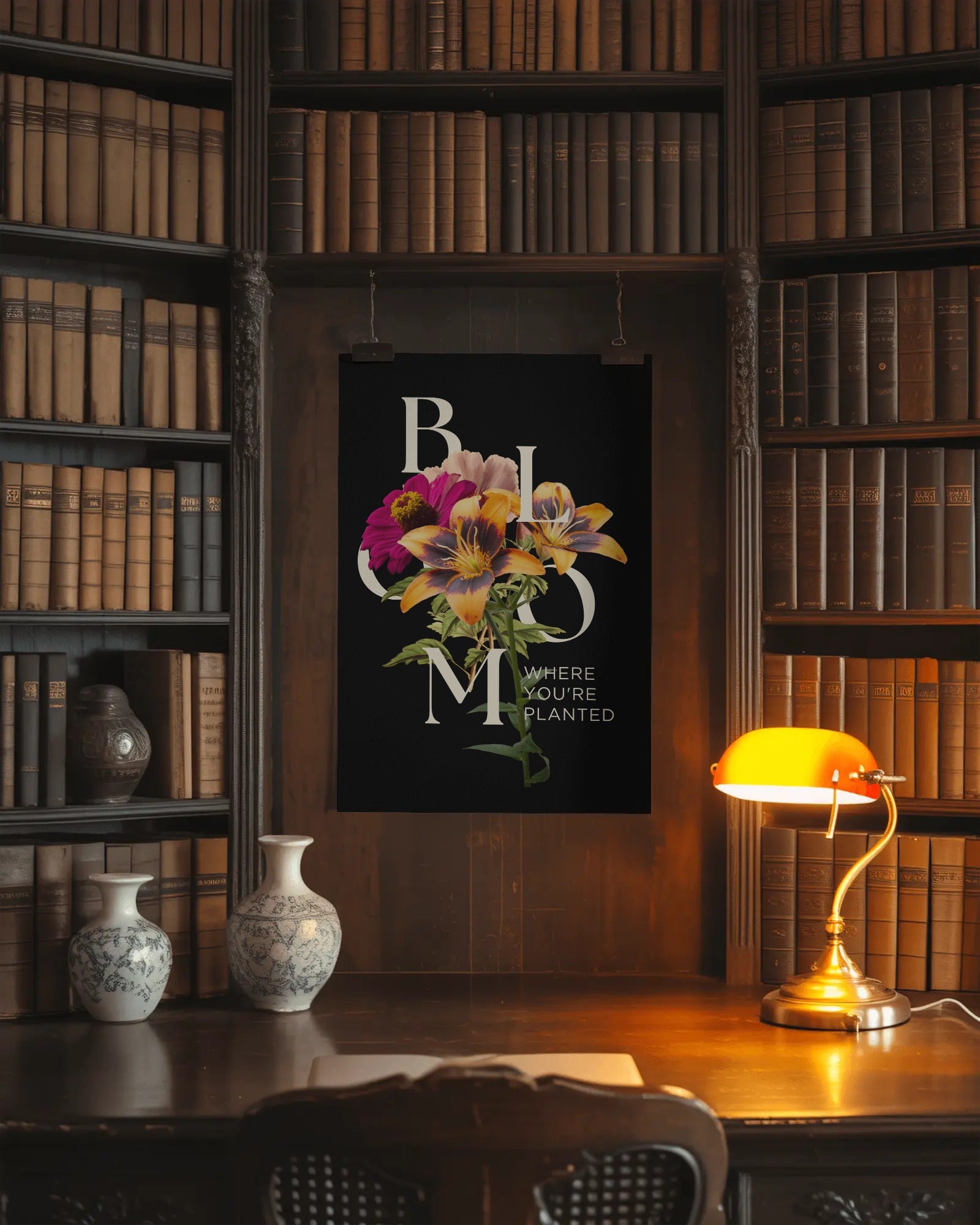 Floral artwork on a wall in a library setting with books and a lamp.