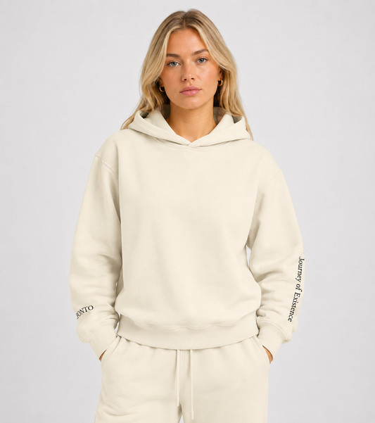 Person wearing a beige hoodie with branding on sleeves against a plain background. Stylist streetwear hoodie, comfy formal hoodie, fashion hoodie, graphic hoodie, no front pocket hoodie, large hooded hoodie, large hood hoodie, oversized hoodie