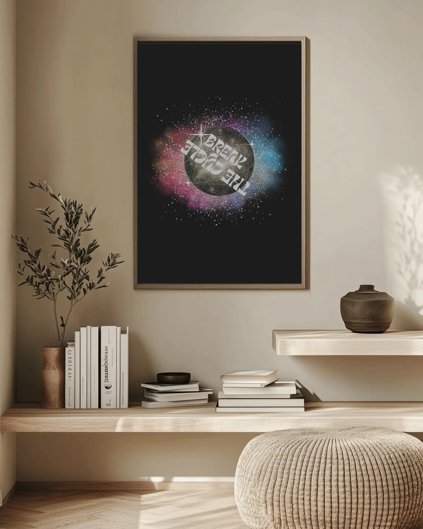 Framed artwork with cosmic design on a wall above a wooden shelf with books and decor.