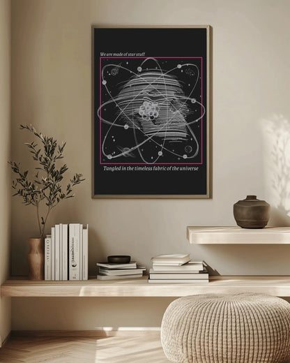 Framed poster of an atom design on a wall above a wooden shelf with books and decor.